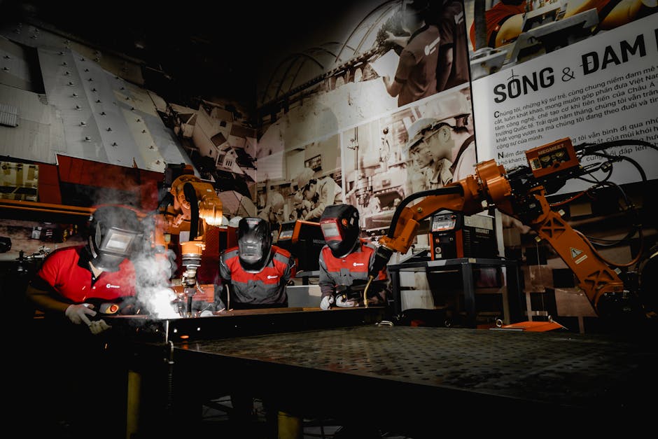 Three welders in protective gear working with robots in a high-tech industrial workshop.