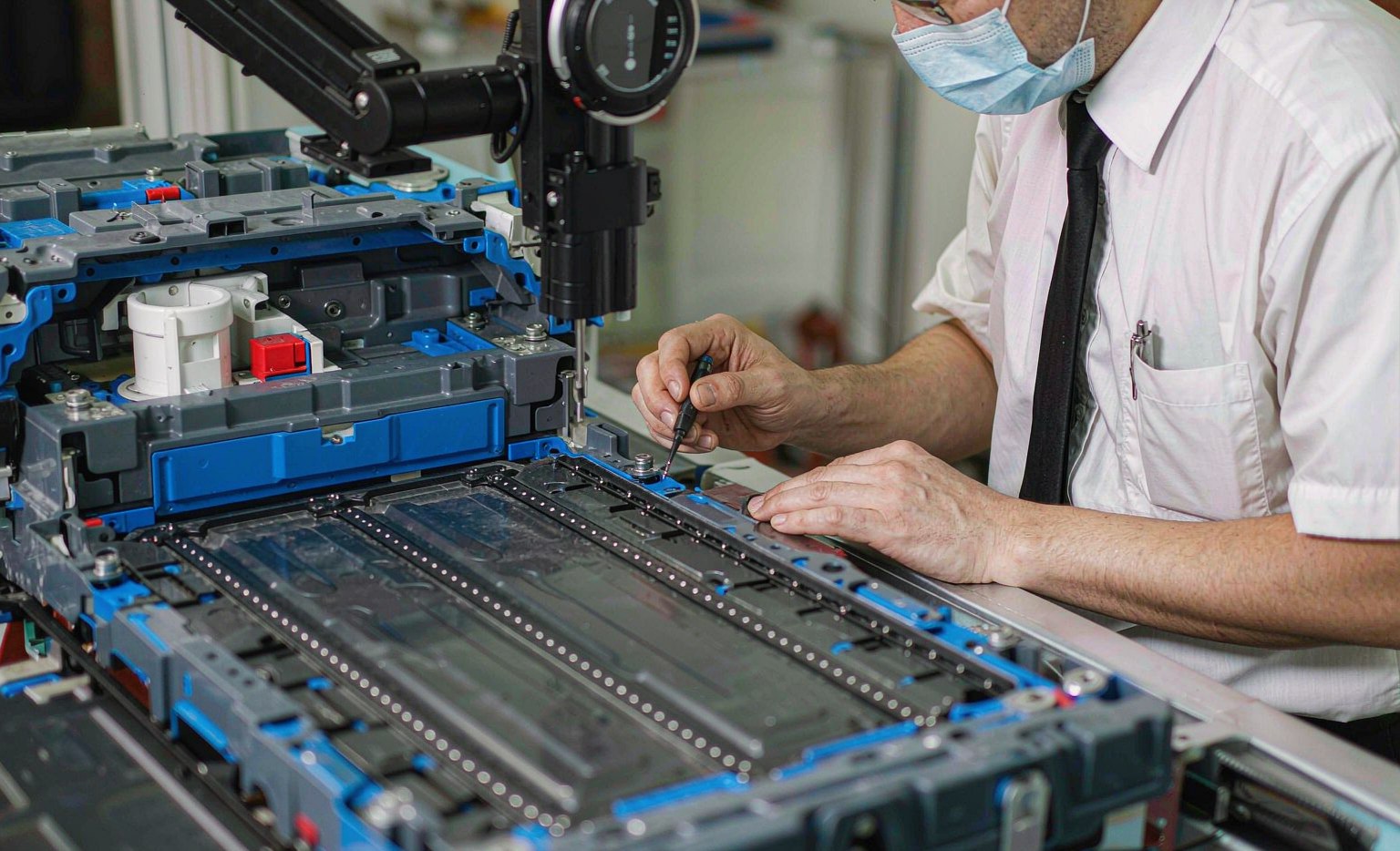 Laser Welding Robots in EV Battery Manufacturing Technician inspecting a laser weld on an EV battery module