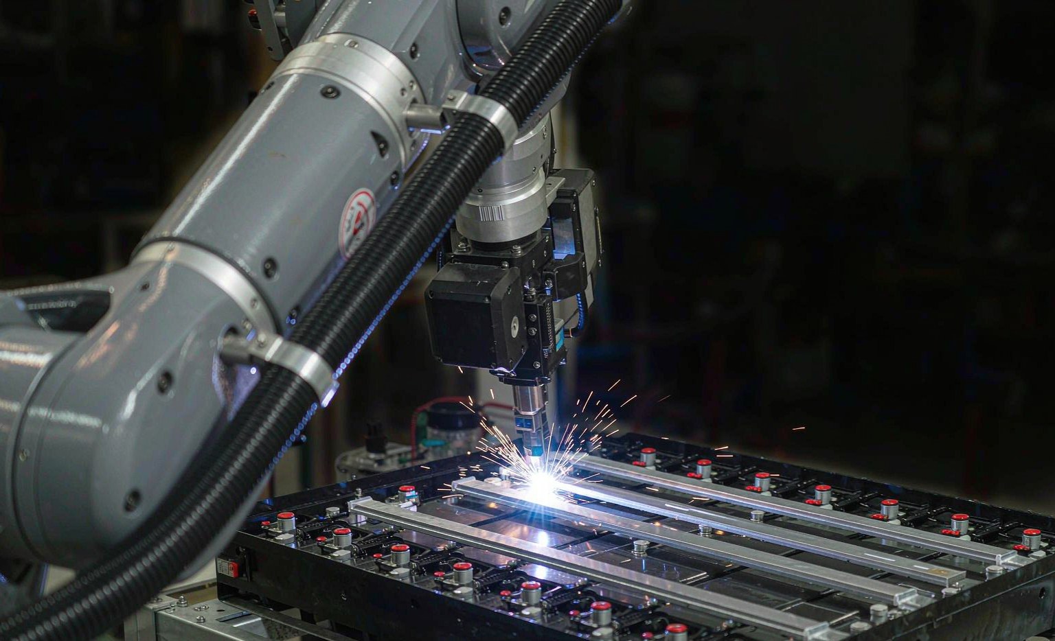 Industrial robot laser welding busbars on an EV battery module