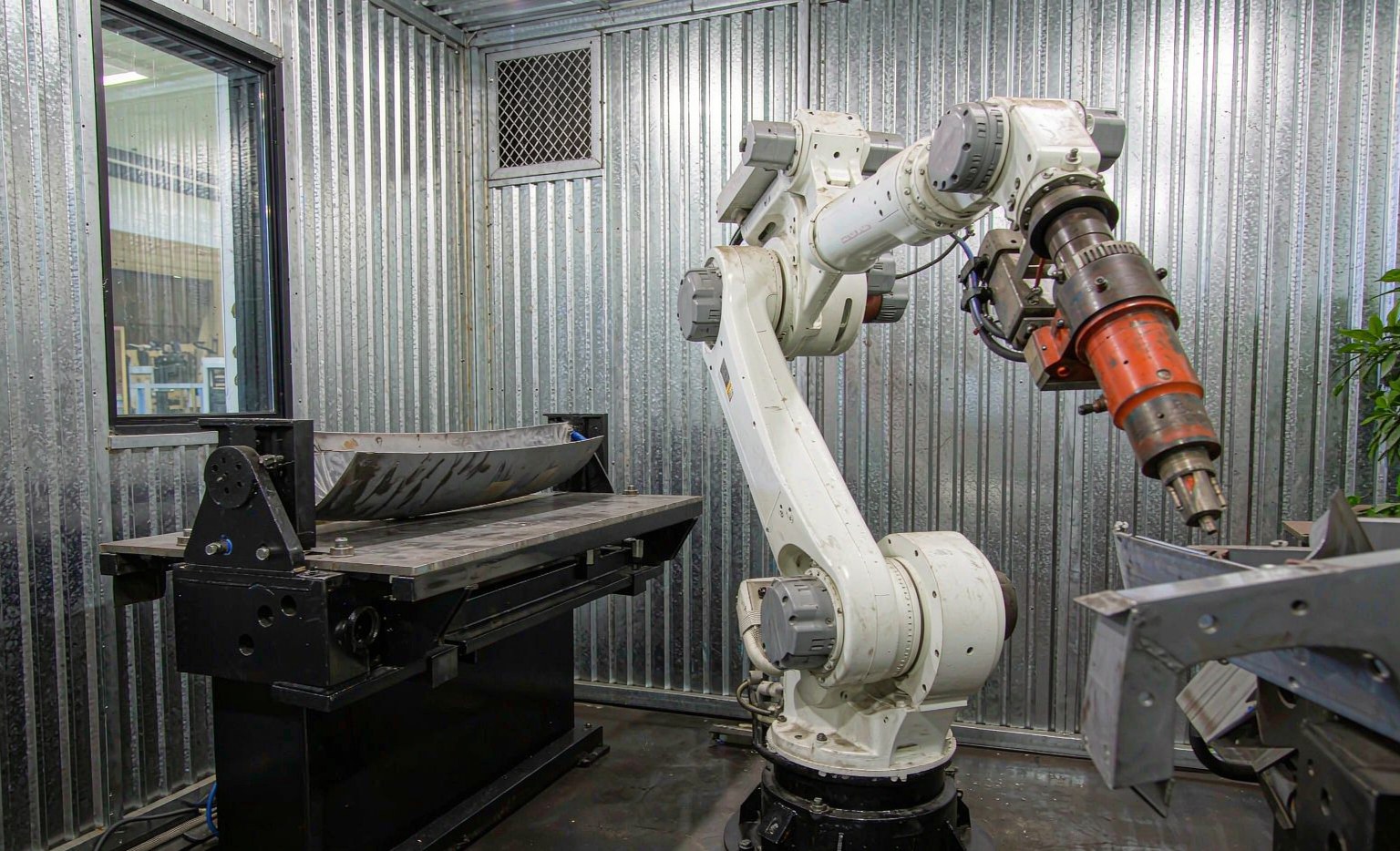 Six-axis welding robot inside a safety enclosure with positioner